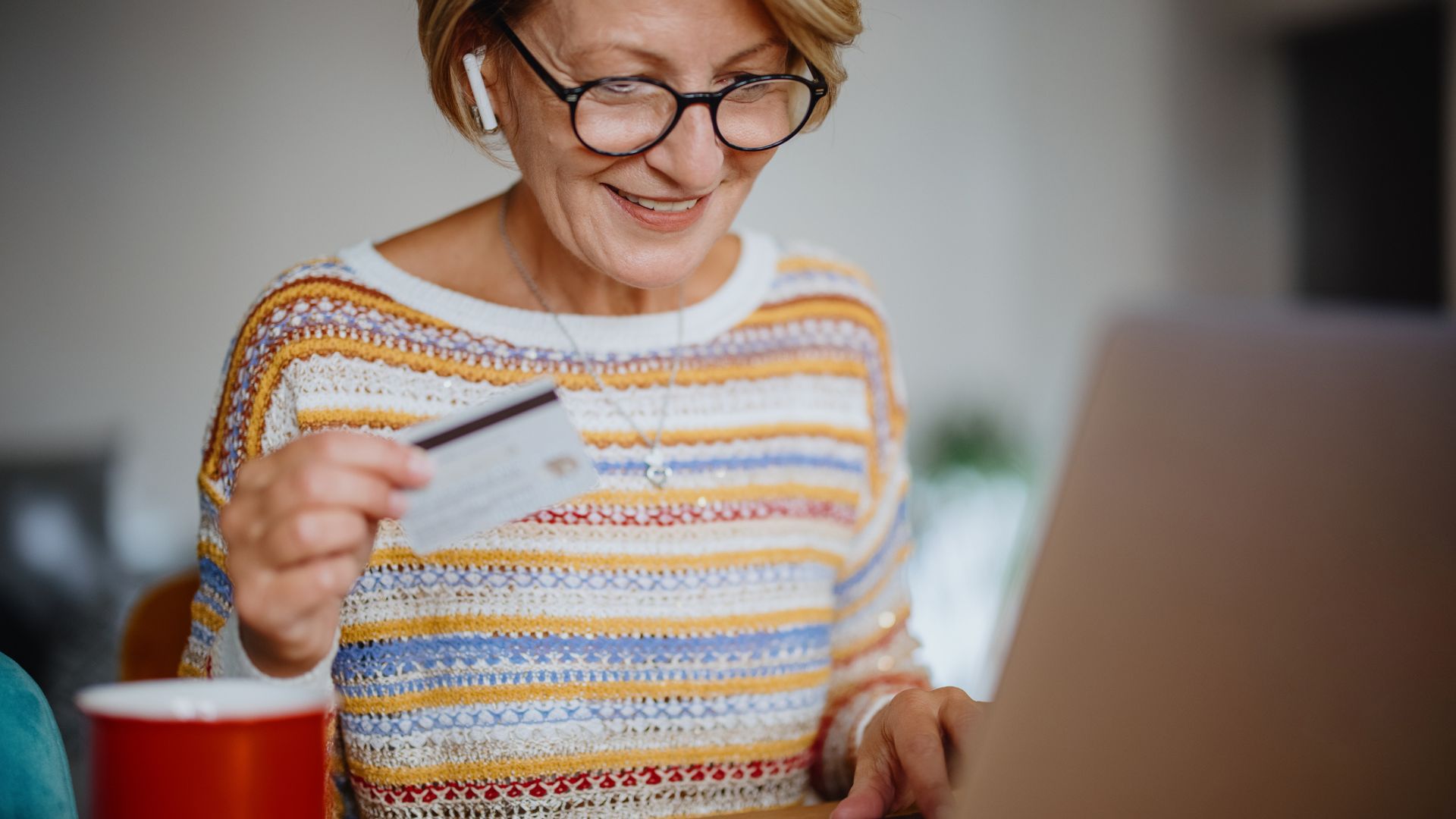 Mature adult woman using laptop and credit card for online Christmas shopping at her home